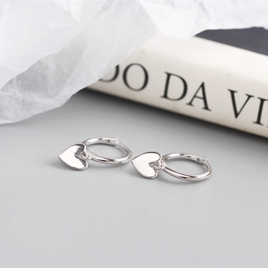 Detailed view of S925 sterling silver heart-shaped hoop earrings on a textured background