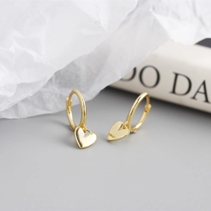 Close-up of golden heart-shaped hoop earrings on a minimalist lifestyle background