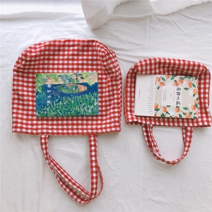 Flat lay of red and white gingham canvas tote bags in two sizes on white fabric