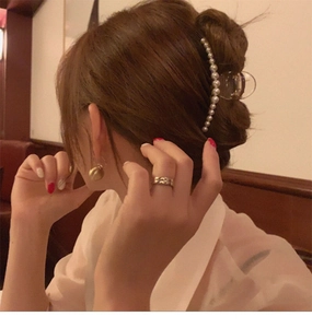 Detail showing a pearl hair claw clip on an updo with elegant gold hoop earrings