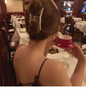 Elegant back view of a woman wearing a transparent pearl claw clip in a warm cafe