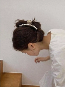 Close-up of elegant white pearl hair claw clip worn on a messy bun hairstyle
