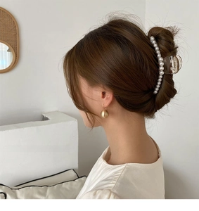 Detail of Korean pearl hair claw clip and gold ball earrings worn by a model