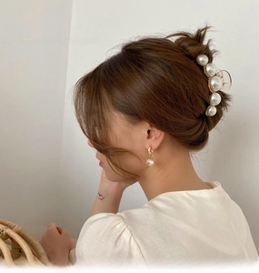 Elegant set of large white pearl hair claw and matching earrings worn by a model