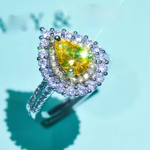 Macro shot of a pear-cut yellow moissanite ring with a double halo on a blue base
