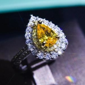 Macro shot of pear-cut yellow moissanite ring with halo setting and starburst effect