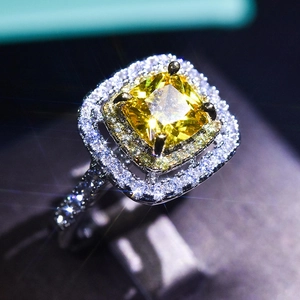 Macro shot of cushion cut yellow gemstone ring with double halo white stones on silver band