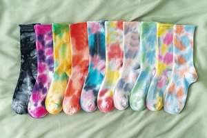 Detailed collection of ten tie-dye cotton crew socks in vibrant assorted colors on green fabric