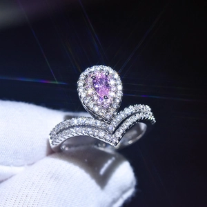 Close-up of V-shaped platinum plated ring with pear-cut pink stone and halo diamonds