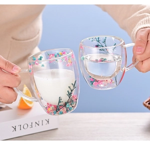 Detail of double wall glass cups with colorful dried flowers holding milk and water