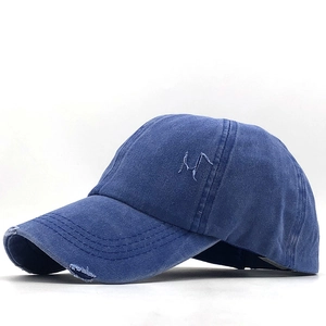Detail shot of distressed dark blue washed cotton baseball cap with torn brim and M stitching
