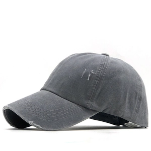 Detail of distressed dark grey baseball cap showing washed cotton texture and ripped holes