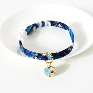 Close-up of blue wave pattern pet collar with golden bell and white buckle on ceramic plate