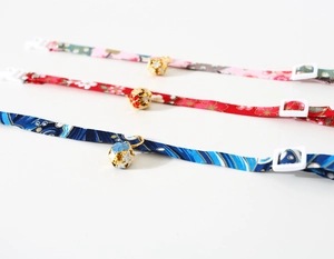 Detail of adjustable pet collars with floral patterns, metal bells and plastic buckles