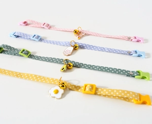 Detail of fabric pet collars with candy-colored charms, plastic buckles, and bells