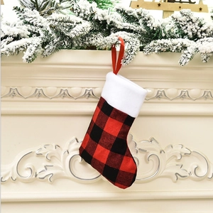Close-up of red and black buffalo plaid Christmas stocking hanging on a snow-covered mantel