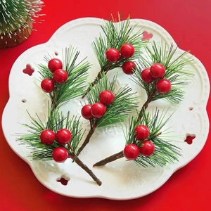 Close-up of 6 artificial pine needles with red berries on a white decorative plate