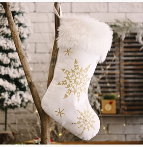 Detail of white plush Christmas stocking with gold snowflake embroidery and pearl accents