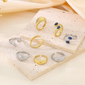 Detail of gold and silver textured stainless steel rings on silk and stone background