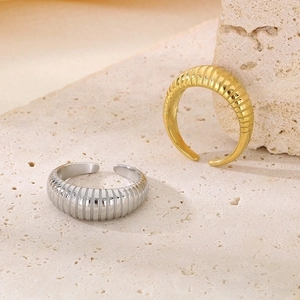 Detailed shot of gold and silver textured croissant rings on a beige stone pedestal