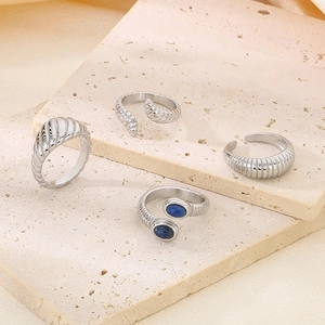 Silver snake-patterned stainless steel open rings with deep blue gemstones on stone tray