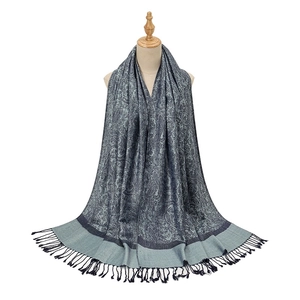 Detail of dark blue paisley scarf with elegant fringe trim on a wooden mannequin