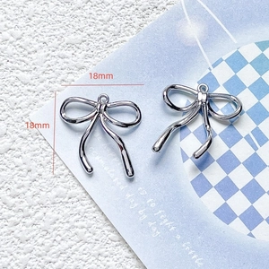 Detailed macro view of 18mm silver bow pendant charms for DIY jewelry making