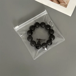 Close-up of black beaded bracelet with tassel inside a thick clear EVA jewelry storage bag