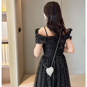 Elegant black sequin mini dress with sheer skirt and a silver heart chain bag accessory
