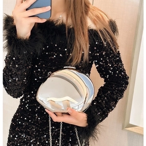 Glossy silver metal oval evening clutch bag with chain strap styled with black party dress