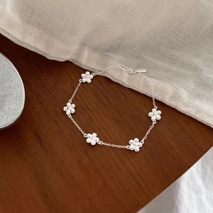 Elegant s925 silver flower bracelet with five small floral charms on a wooden background