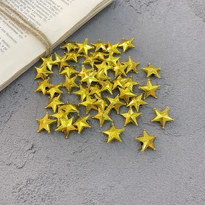 Golden 2cm plastic star toppers for Christmas cakes and trees scattered on a gray surface