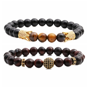 Dettaglio del set di braccialetti con pietre occhio di tigre e ciondolo a corona oro