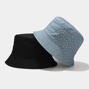 Detail view of double-sided bucket hats in solid black and floral print with stitch detail