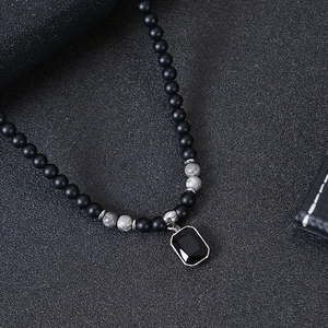 Detail of matte black beads and tiger eye stones with a black gemstone pendant necklace