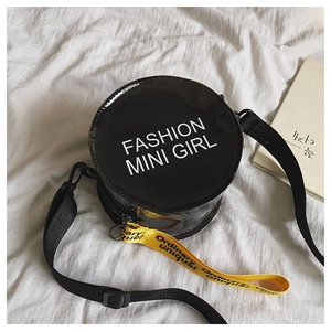 Detail of round black glossy bag with Fashion Mini Girl print and yellow strap