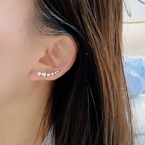 Detailed view of silver curved bead ear cuff showing seven gradient beads on model ear
