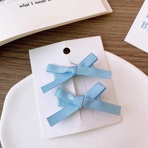 Close-up of light blue satin ribbon bow hair clips set of two on white display card