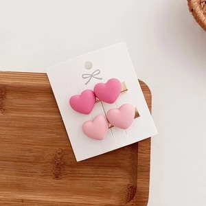 Set of four matte pink heart-shaped hair clips displayed on a white branded card