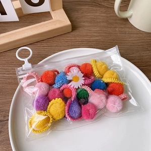 Close-up of colorful plush hair ties in a daisy-themed zipper bag on a wooden table