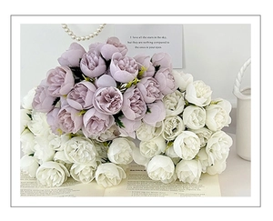 Detail of faux tea rose bouquets in purple-grey and white colors over an open book