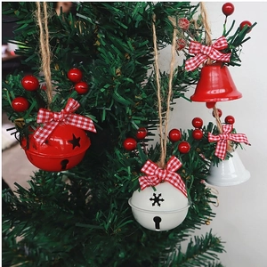 Christmas tree ornaments with red and white bells, pine cones, berries and twine bow