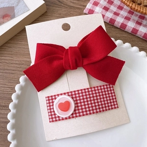 Détail d'un nœud rouge festif et de barrettes à carreaux sur carte MiYU