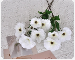 Top view of white artificial poppy flowers with silk petals on knit fabric background