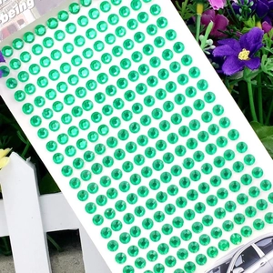 Macro shot of 3mm green round acrylic rhinestones on self-adhesive backing sheet