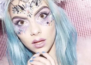 Detail of colorful acrylic face gems on a model with purple eye makeup for a masquerade
