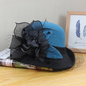 Detail of wool cloche hat with black flower, mesh veil and beads on a wooden desk