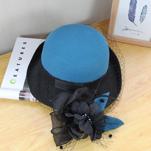 Detail of wool fedora hat with elegant peacock blue crown, black mesh veil and floral decor
