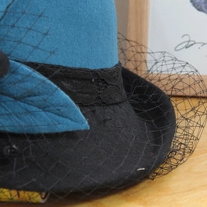 Detail of teal wool felt vintage hat featuring black lace trim and delicate mesh veil