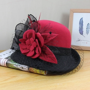 Detail of vintage wool felt cloche hat featuring red fabric flower and black mesh veil
